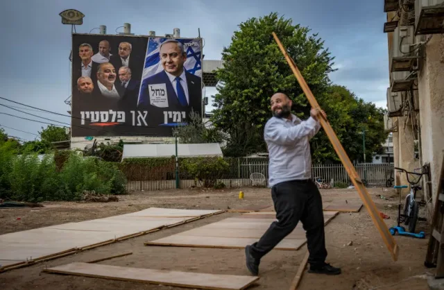 Israelis dismantle their sukkahs next to a Likud campaign poster carrying the slogan "Right or Palestine" in Ashdod on October 5, 2026 (Yonatan Sindel/Flash90 via The Jerusalem Post)